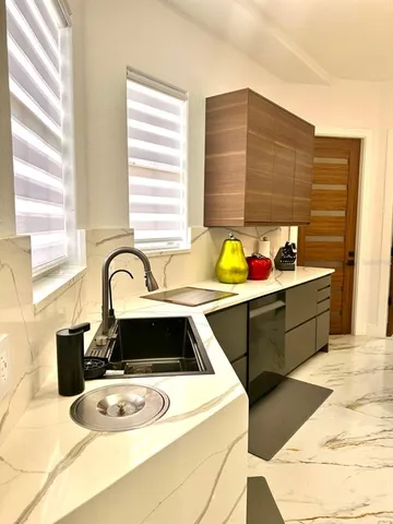 a kitchen with granite countertop a sink a stove and cabinets