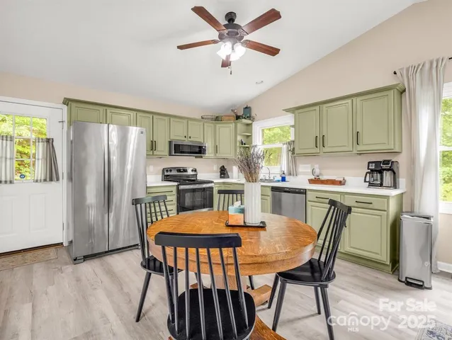 a kitchen with stainless steel appliances granite countertop a dining table chairs refrigerator and cabinets