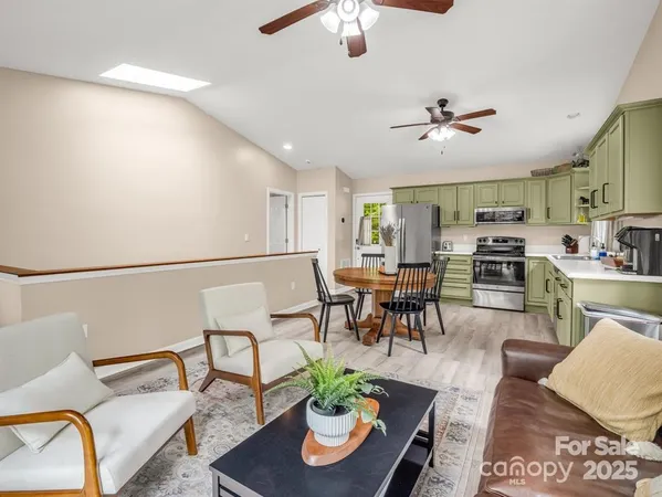 a living room with furniture kitchen view and a chandelier