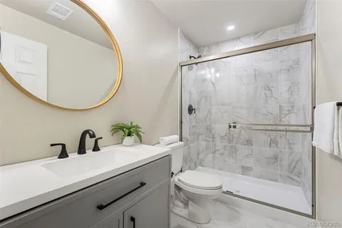 a bathroom with a sink a mirror a toilet and shower