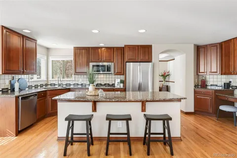 a kitchen with stainless steel appliances kitchen island granite countertop a table chairs microwave and sink
