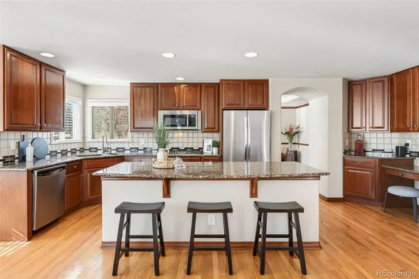 a kitchen with stainless steel appliances kitchen island granite countertop a table chairs microwave and sink
