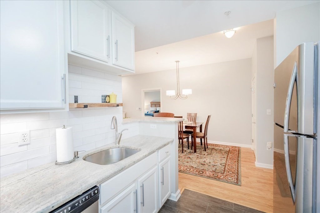 38 Village Road, Unit 312 Middleton, MA 01949 - Photo 13 of 42 a kitchen with sink cabinets and dining table