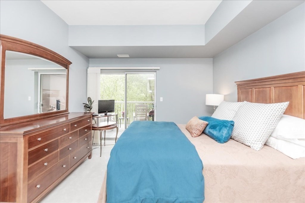 38 Village Road, Unit 312 Middleton, MA 01949 - Photo 23 of 42 a bedroom with a bed and wooden floor