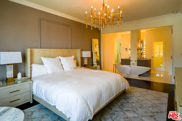 a bedroom with a large bed and a chandelier