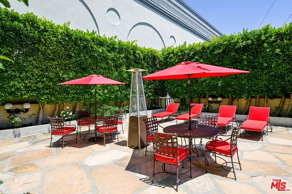 an outdoor space with patio lots of white furniture and umbrella