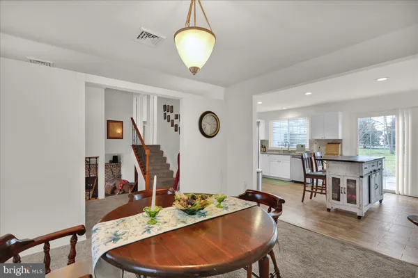 a dining room with wooden floor a chandelier a wooden table and chairs
