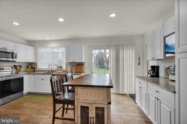 a kitchen with granite countertop a stove top oven a sink dishwasher a dining table and chairs with wooden floor