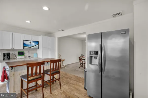 a dining area with stainless steel appliances kitchen island granite countertop a refrigerator a stove a microwave oven with white cabinets and wooden floor