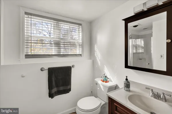 a bathroom with a toilet a sink a mirror and a window