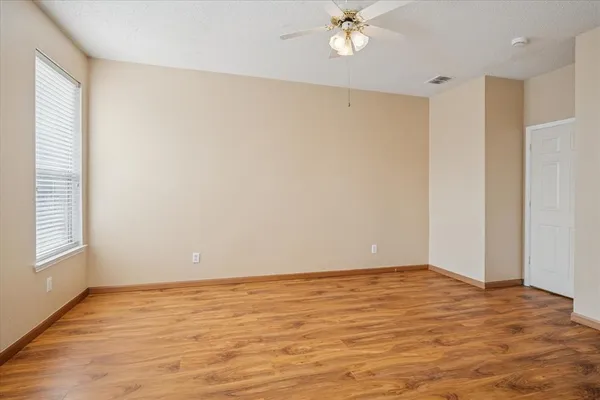 a view of an empty room with wooden floor and a window