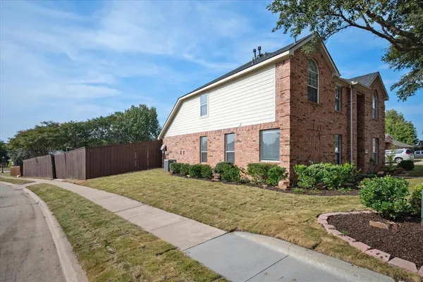 a view of a brick house next to a yard with potted plants