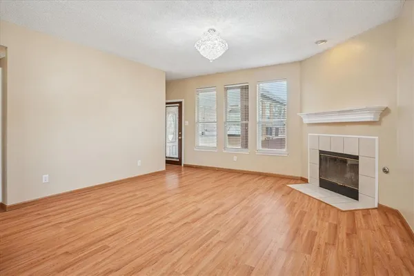 an empty room with wooden floor fireplace and windows