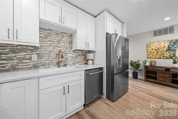 a kitchen with stainless steel appliances white cabinets a refrigerator a sink a stove a microwave and wooden floors