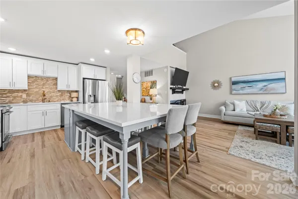 a kitchen with stainless steel appliances a dining table chairs and wooden floor