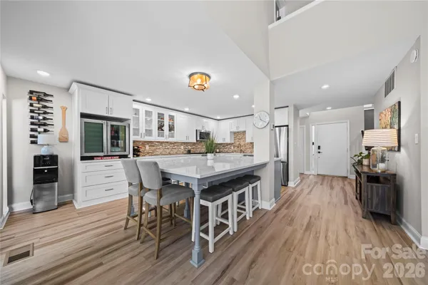 a kitchen with stainless steel appliances granite countertop a dining table chairs and wooden floor