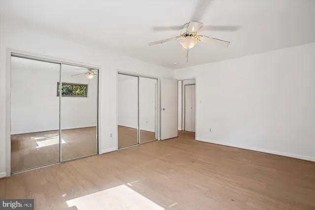 a view of an empty room with a ceiling fan and window