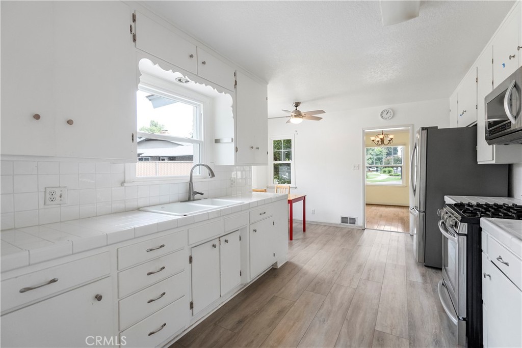 4669 Edgewood Place Riverside, CA 92506 - Photo 5 of 26 a large white kitchen with cabinets a stove a sink and a refrigerator