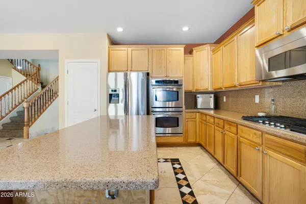 a kitchen with stainless steel appliances granite countertop a refrigerator a stove and a sink with wooden cabinets