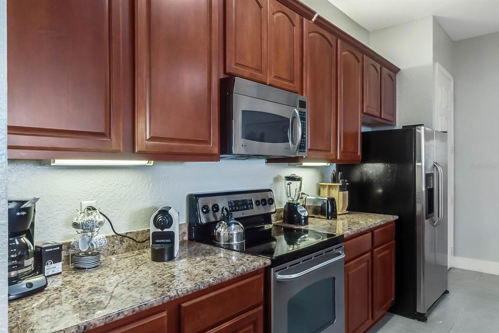 5049 Shoreway Loop, Unit 40601 Orlando, FL 32819 - Photo 16 of 28 a kitchen with stainless steel appliances granite countertop a sink stove and microwave