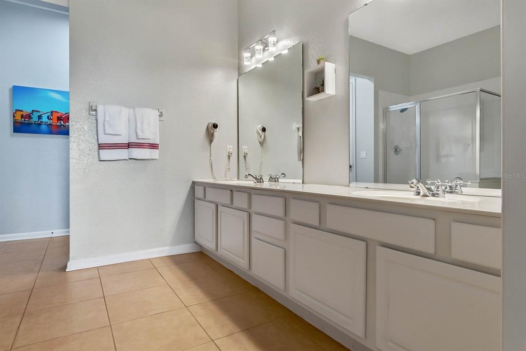 5049 Shoreway Loop, Unit 40601 Orlando, FL 32819 - Photo 17 of 28 a bathroom with a double vanity sink a mirror and a shower
