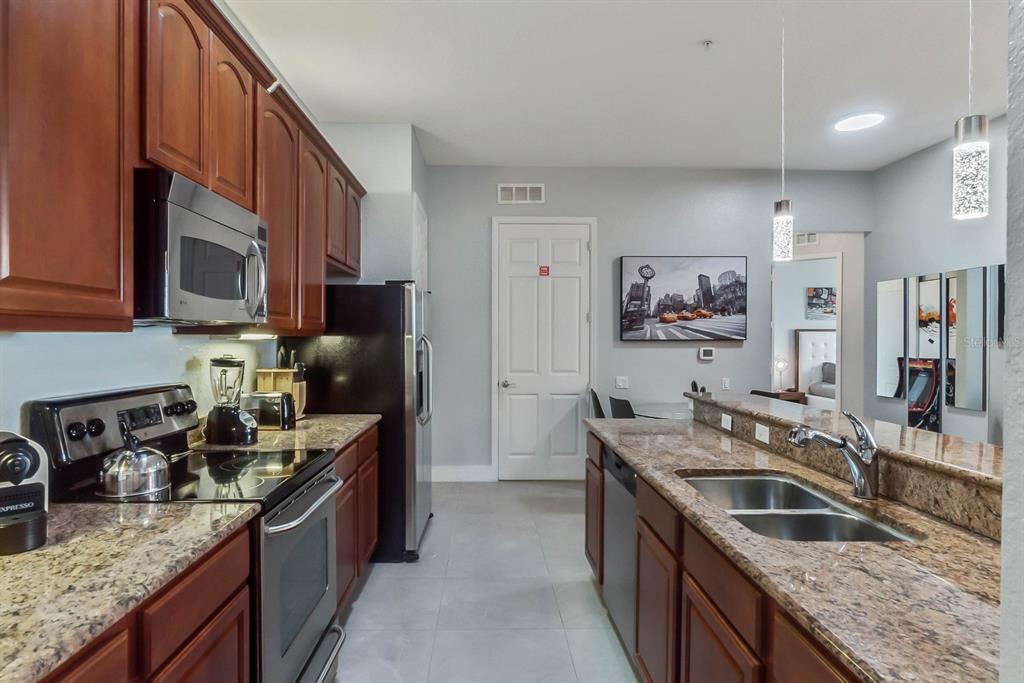 5049 Shoreway Loop, Unit 40601 Orlando, FL 32819 - Photo 5 of 28 a kitchen with granite countertop stainless steel appliances a sink dishwasher a refrigerator a stove top oven and a counter space