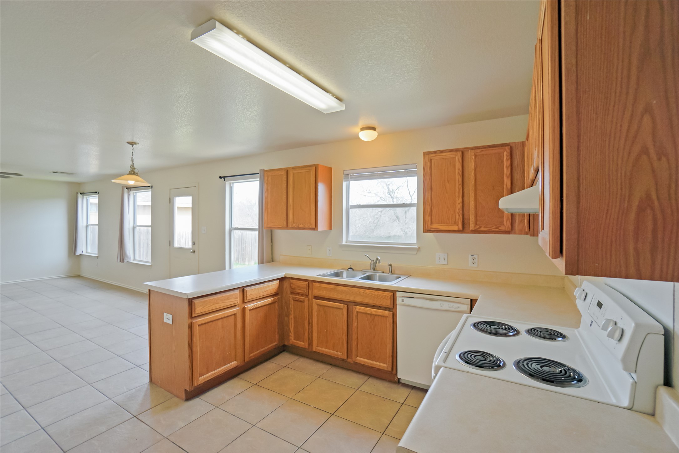 714 Lavaca Loop Elgin, TX 78621 - Photo 38 of 38 Kitchen featuring white appliances, light countertops, a peninsula, open floor plan, and light tile patterned flooring