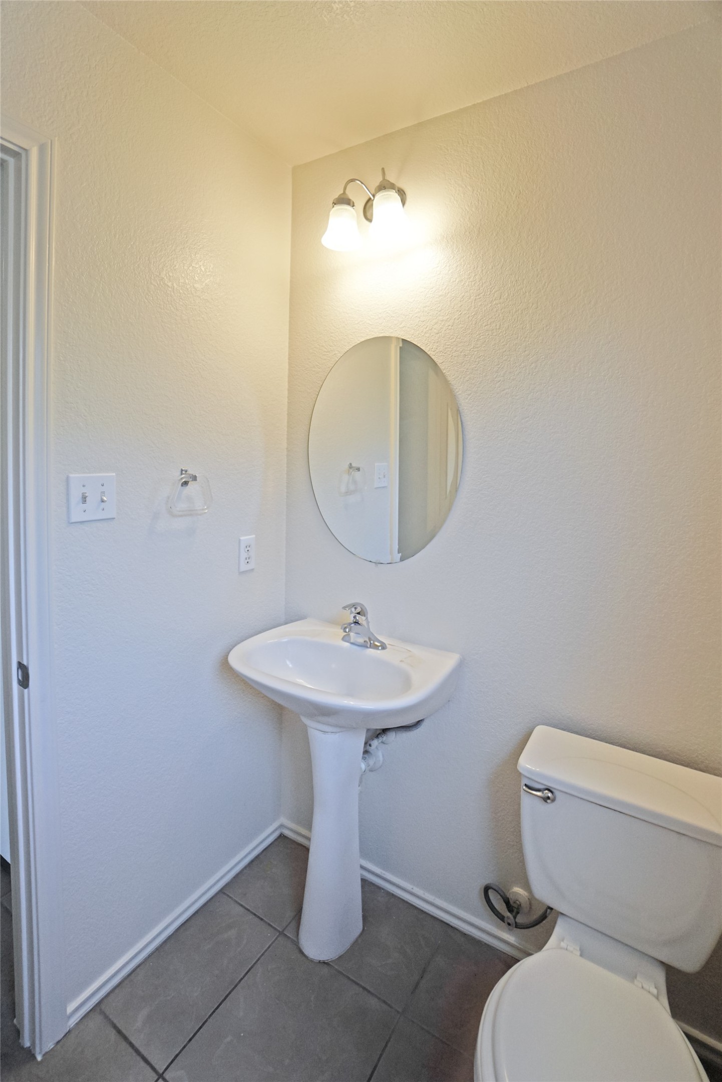 714 Lavaca Loop Elgin, TX 78621 - Photo 8 of 38 Half bathroom featuring dark tile patterned flooring and a textured wall