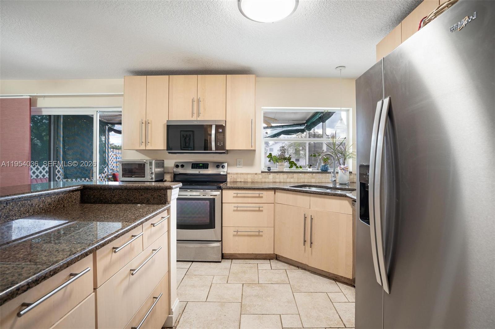 13930 Oak Ridge Drive Davie, FL 33325 - Photo 14 of 54 a kitchen with granite countertop a stove a sink and a refrigerator