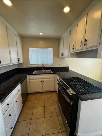 a kitchen with granite countertop white cabinets and black appliances