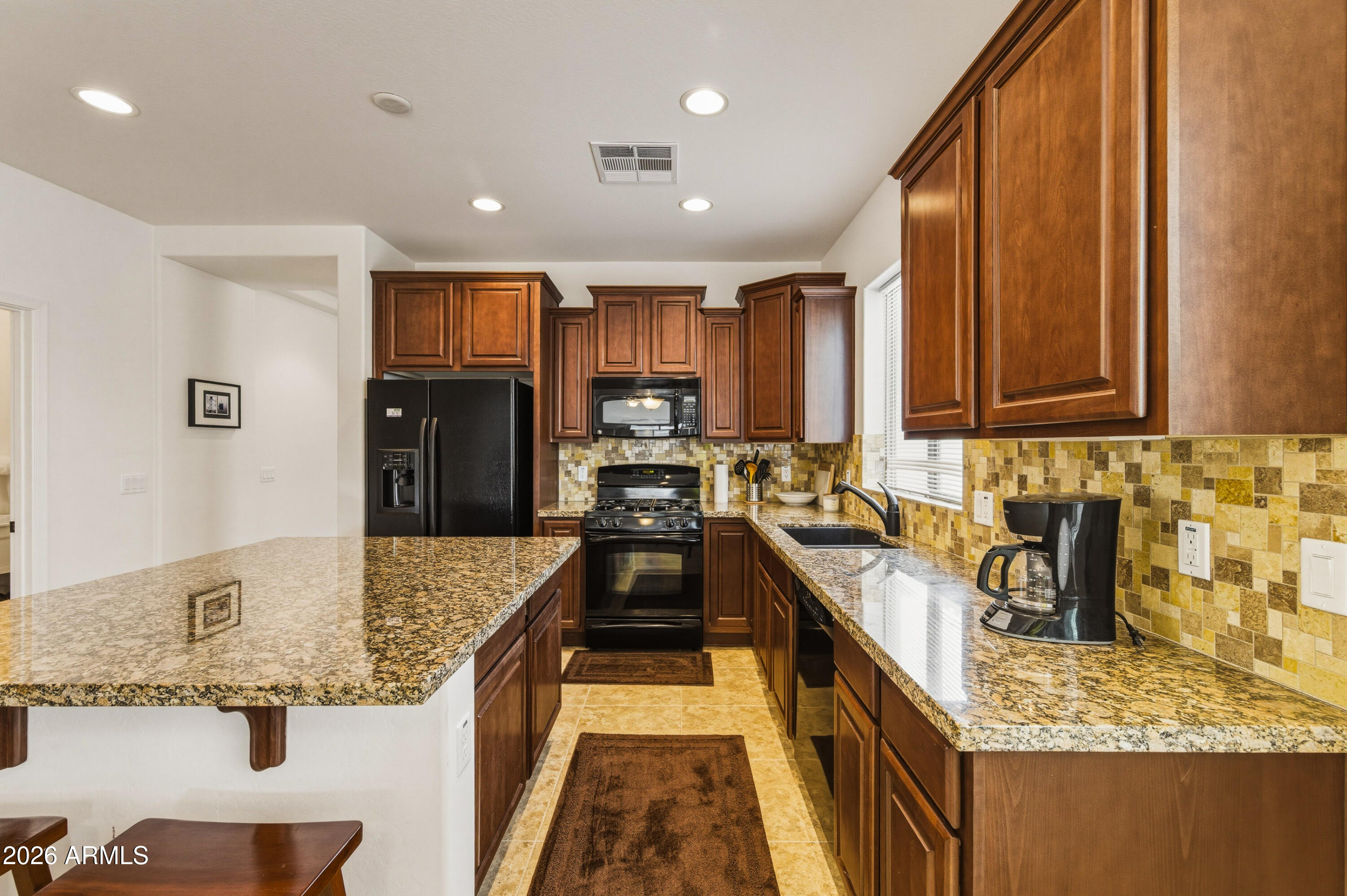 38061 West Merced Street Maricopa, AZ 85138 - Photo 16 of 49 a kitchen with stainless steel appliances granite countertop a sink stove and refrigerator