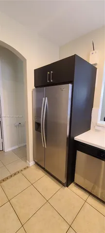 a view of a refrigerator in kitchen and an empty room