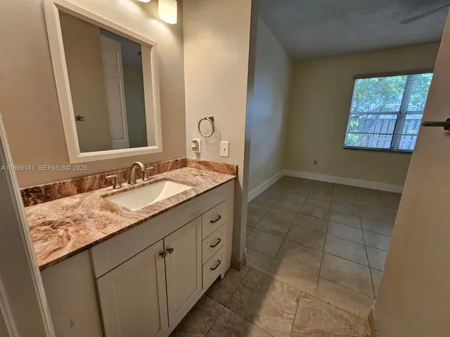 a bathroom with a granite countertop sink a mirror and a bathtub