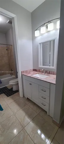 a bathroom with a granite countertop bathtub shower sink vanity and toilet