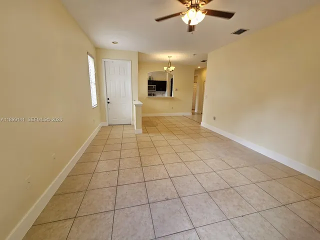 a view of a livingroom with a chandelier fan and kitchen view