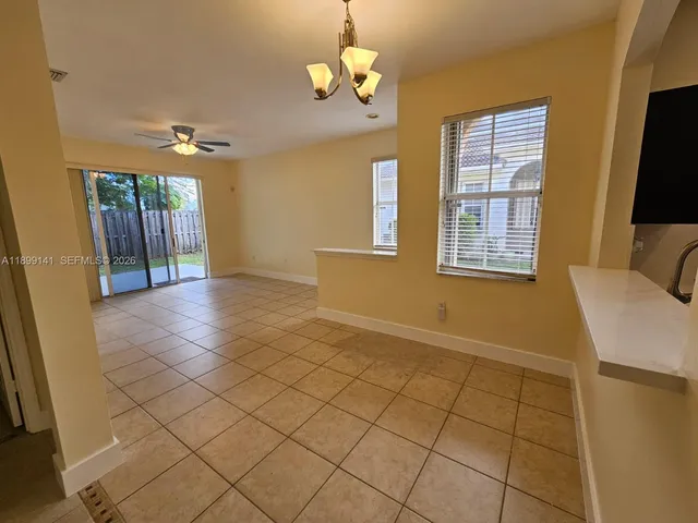 a view of an empty room with window and chandelier fan