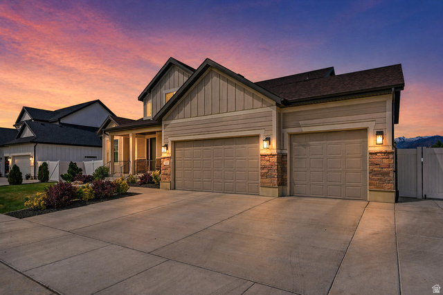 1434 West Stable Street Lindon, UT 84042 - Photo 3 of 76 AI enhanced twilight. View of front facade with an attached garage, driveway, board and batten siding, and a gate