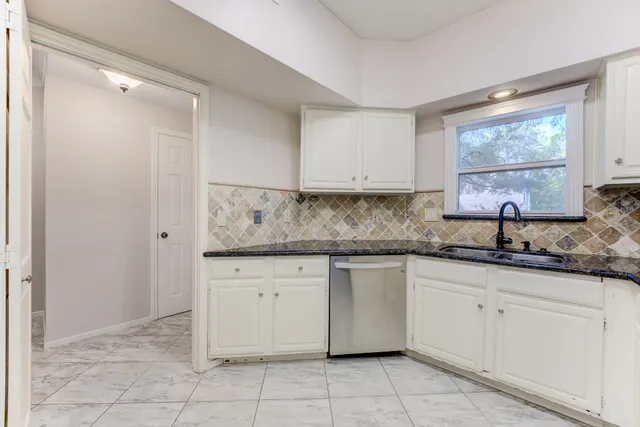 a kitchen with granite countertop white cabinets white appliances with a sink and dishwasher