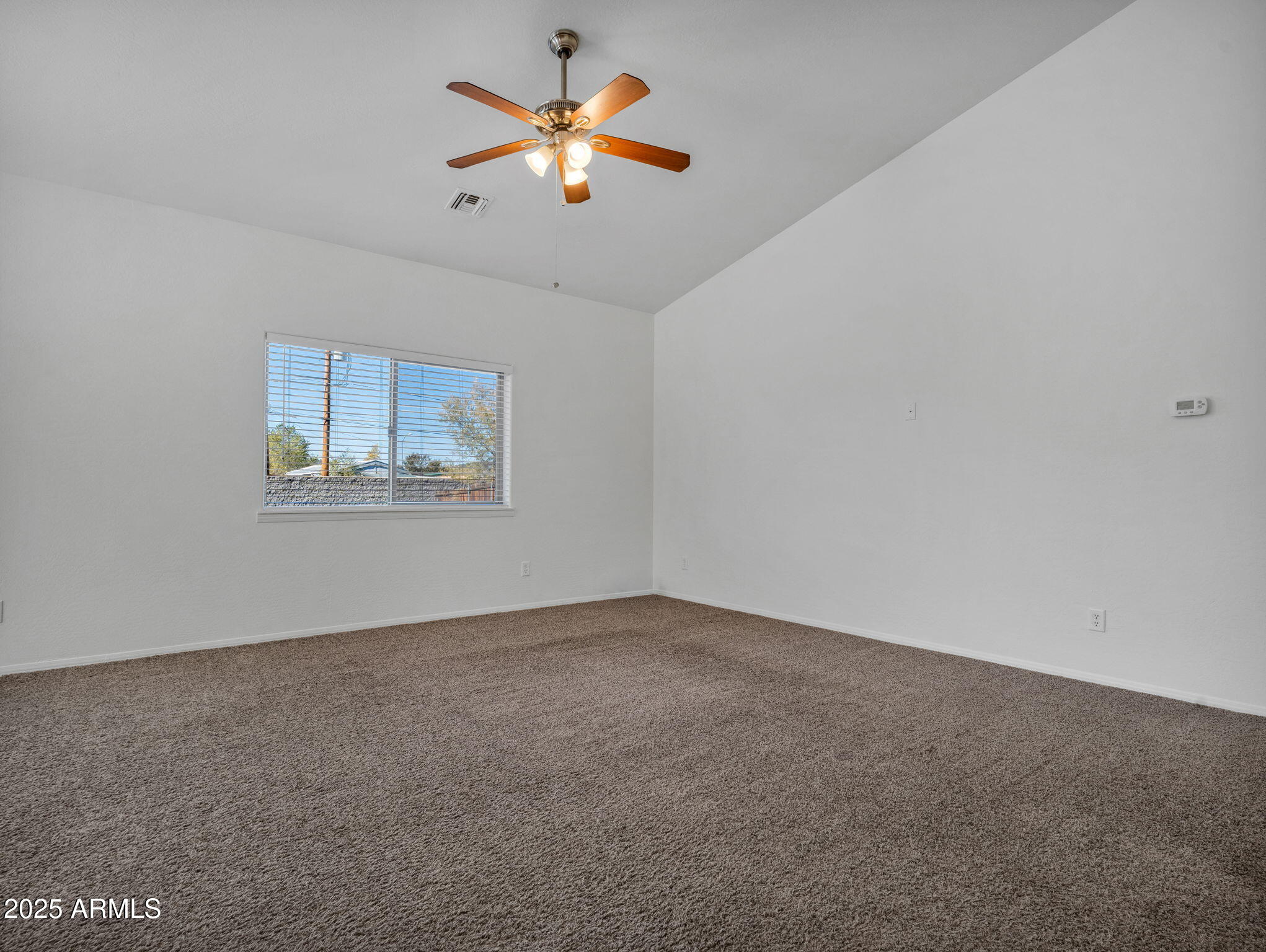 907 Quarter Horse Road Williams, AZ 86046 - Photo 5 of 26 an empty room with a window and a ceiling fan