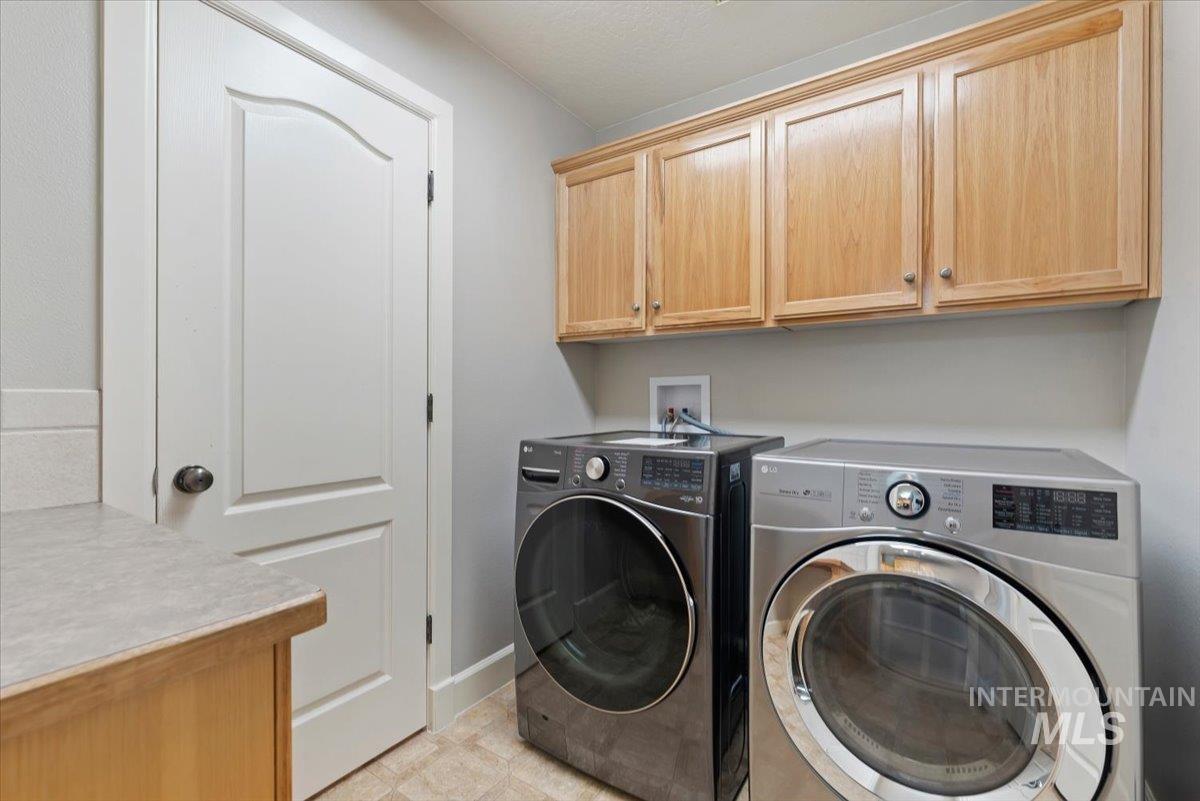 24240 Tiger Lane Caldwell, ID 83607 - Photo 17 of 50 Wall-mounted wood cabinetry, light-toned countertop, and tiled flooring. Washer and Dryer included if buyer needs them. One of them is new.