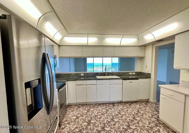 a kitchen with granite countertop a sink a stove a refrigerator and cabinets