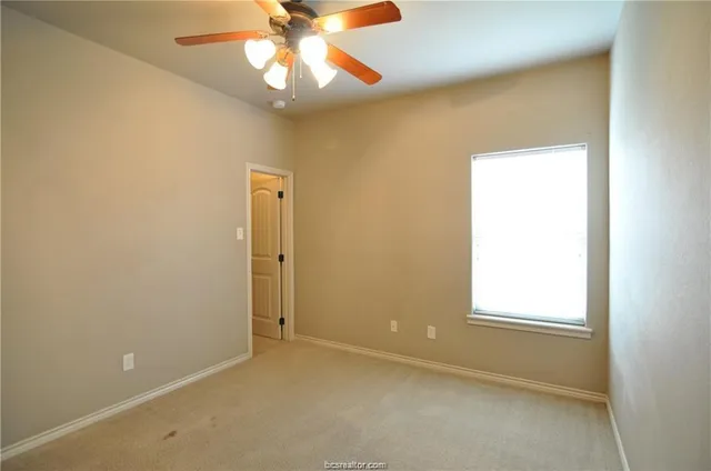 an empty room with a window and a chandelier fan