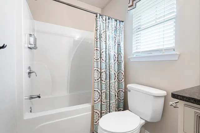 a bathroom with a granite countertop toilet sink and mirror