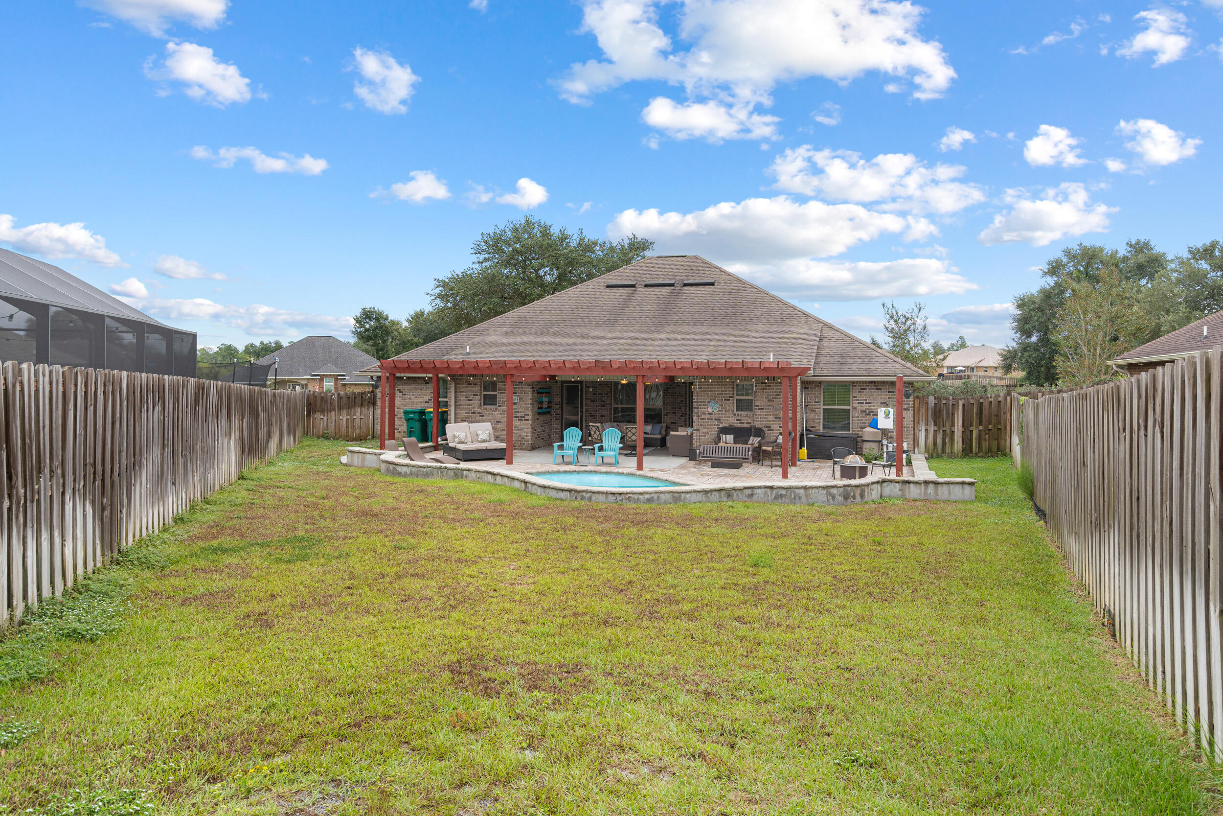 4646 Chanan Drive Crestview, FL 32539 - Photo 47 of 56 a view of a swimming pool with table and chairs under an umbrella with wooden fence