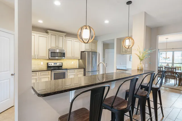 a kitchen with stainless steel appliances granite countertop a stove a sink a dining table and chairs with wooden floor