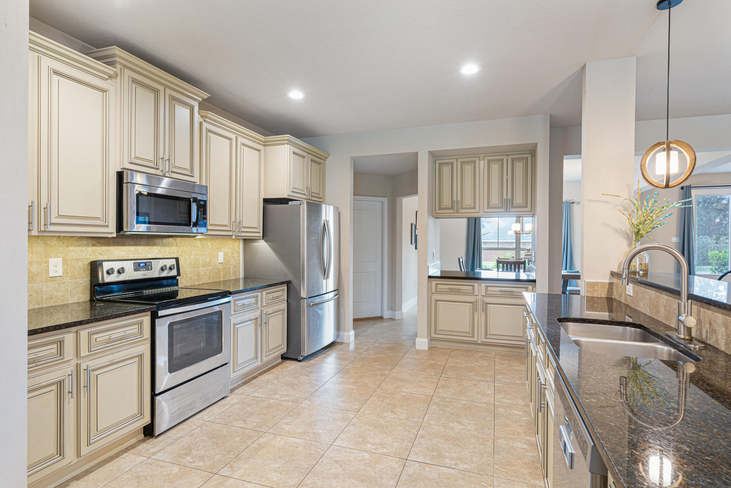 4646 Chanan Drive Crestview, FL 32539 - Photo 10 of 56 a kitchen with stainless steel appliances granite countertop a stove top oven a sink dishwasher a dining table and chairs with wooden floor