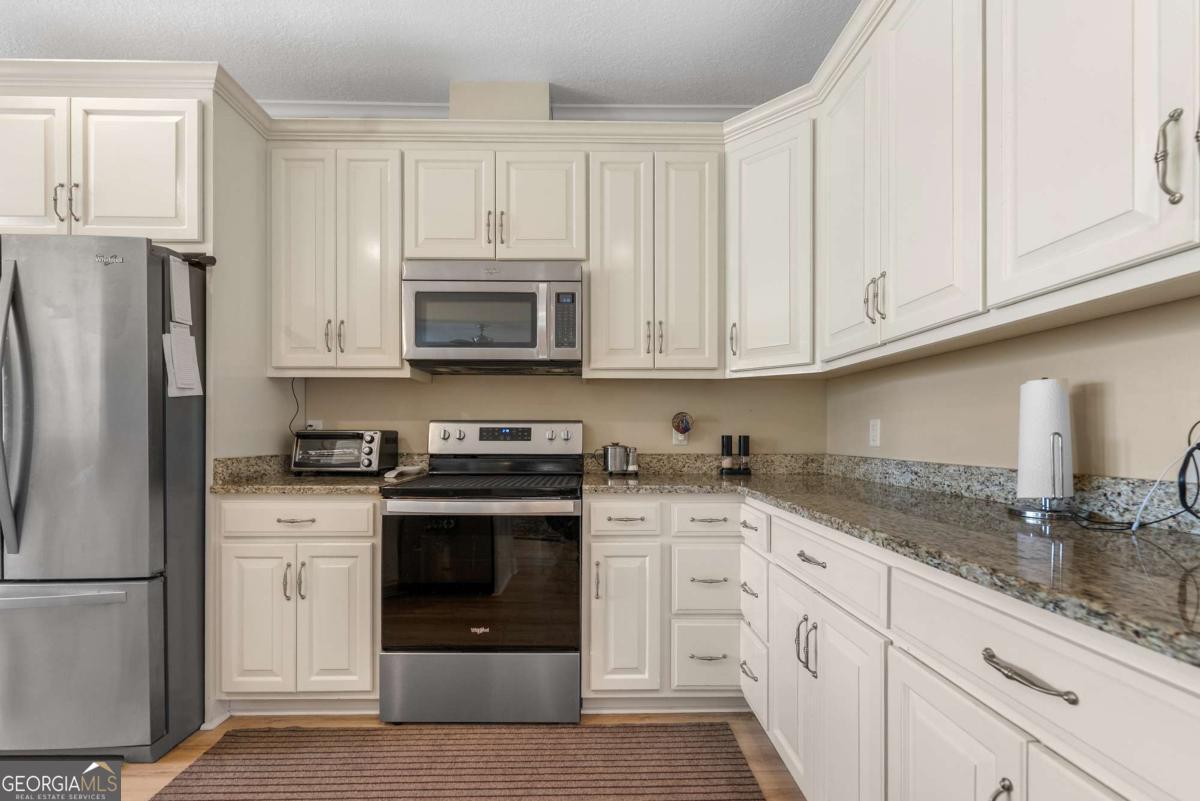 105 Plantation Pnes Drive Blackshear, GA 31516 - Photo 22 of 48 a kitchen with granite countertop white cabinets and stainless steel appliances