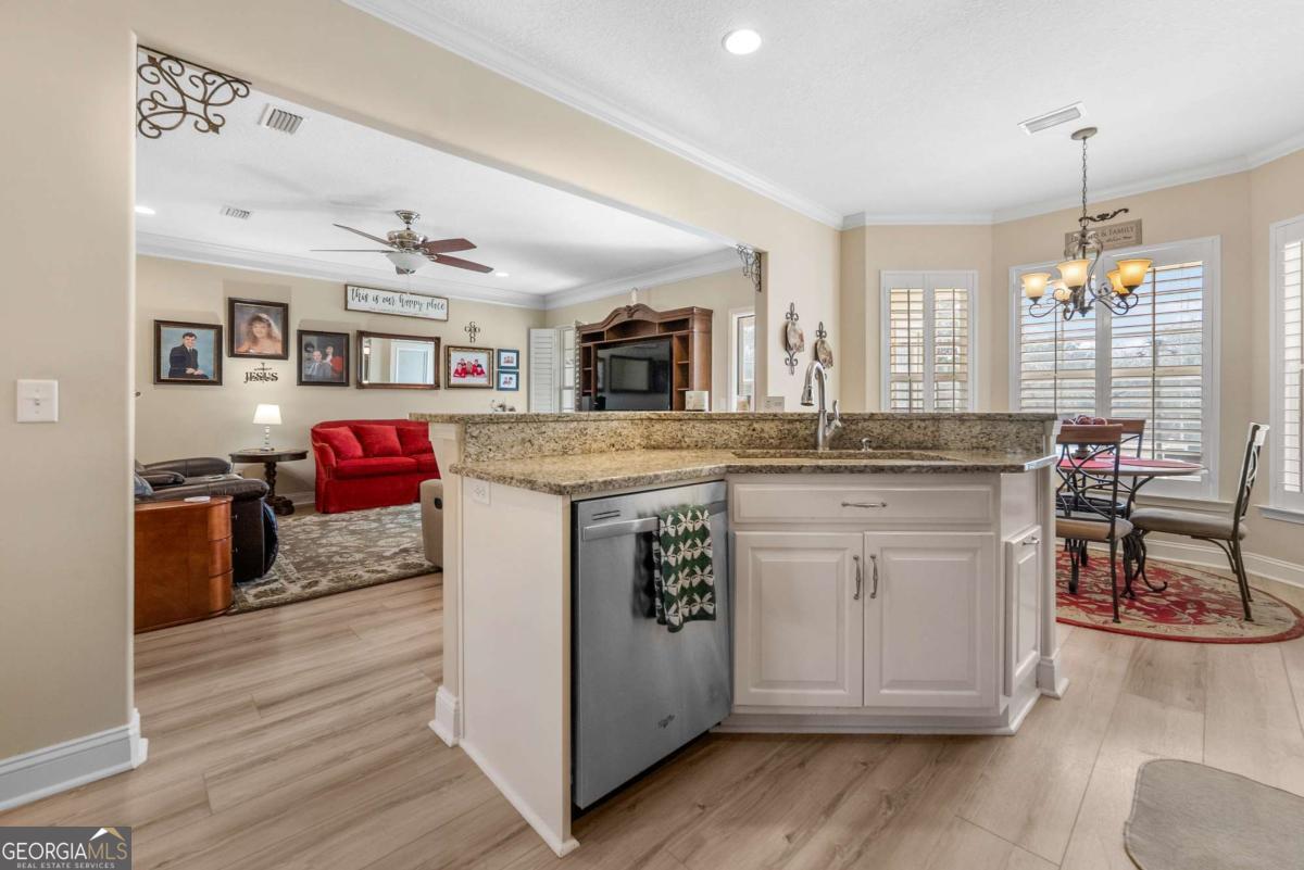 105 Plantation Pnes Drive Blackshear, GA 31516 - Photo 26 of 48 a kitchen with kitchen island granite countertop wooden cabinets and white appliances