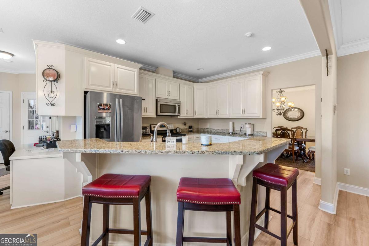 105 Plantation Pnes Drive Blackshear, GA 31516 - Photo 27 of 48 a kitchen with stainless steel appliances granite countertop a kitchen island a table and chairs in it