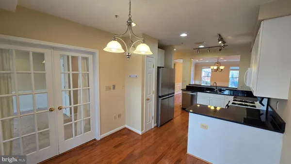 a kitchen with kitchen island granite countertop stainless steel appliances a stove refrigerator and wooden floor